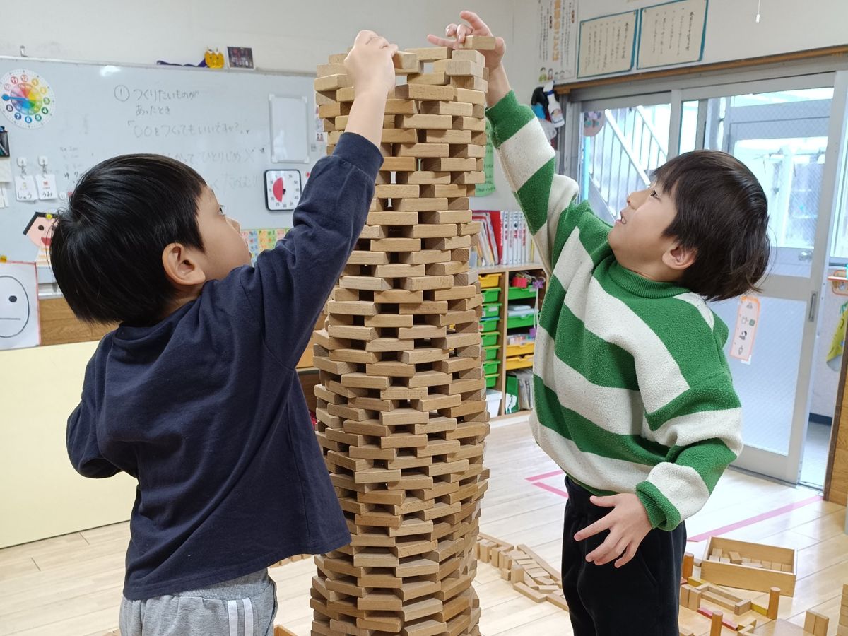 積み木を高く積み上げる子どもたち