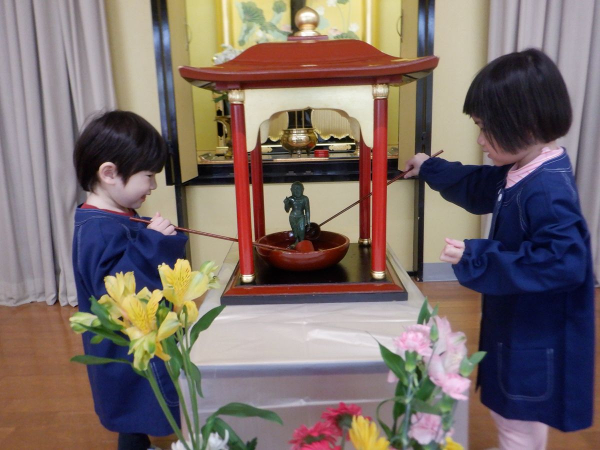 花まつりで誕生仏に甘茶をかける子どもたち